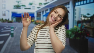 Mağazaların dışındaki mavi bir sokakta elinde ev anahtarlığı tutan beyaz bir kadın. Yeni ev heyecanı..