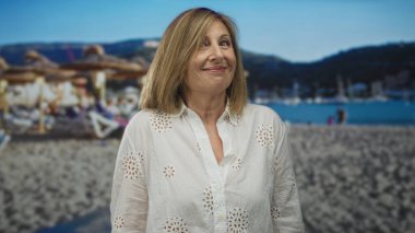 Yüzü öne dönük gülümseyen kadın ve parlak güneş ışığı altında hafif baş eğik; dinginlik.