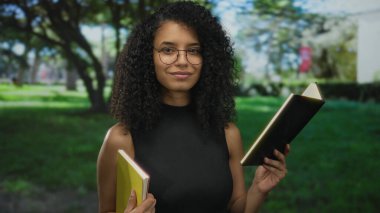 Güneşli bir parkta kitap okuyan bir kadın, yeşillik ve açık hava manzarasıyla çevrili, kendine güven ve merak saçan bir kadın..