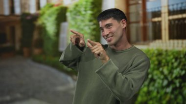 Yeşil kazaklı bir kaldırım taşı sokakta elleri hareket halinde dans eden adam; mutluluk enerjiyi kutluyor..