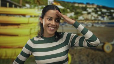 Deniz kıyısında gülümseyen genç İspanyol kadın. Sarı kanoları ve güneşli bir gökyüzünün altında canlı bir açık hava manzarası var.