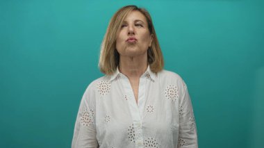 Kadın stüdyo ortamında dudaklarını büzüştükten sonra elleriyle kalp hareketi yapıyor..