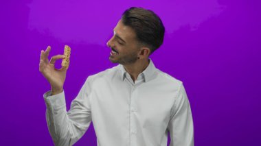 Adam sıcak gülümseme ve granola bar tutarak stüdyoda el kaldırarak tımarlı sakal; sağlıklı yeme neşe.
