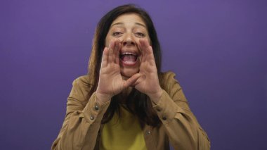 Orta yaşlı İspanyol kadın, elleri kolları bağlı bağırıyor ve mor stüdyo ortamında ağzını açıyor; coşku.