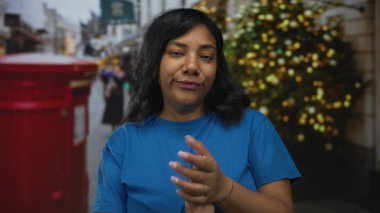 Kadın, festival ışıklarıyla süslenmiş kalabalık şehir caddesinde el çırpıyor; cesaret cemiyeti.