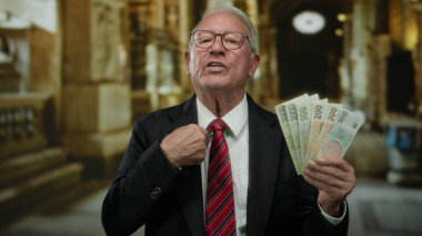 Kilise içinde Czech Koruna banknotları tutan kıdemli bir adam, dini bir ortamda iş ve zenginliği simgeliyor..