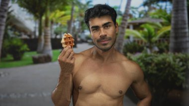 Genç İspanyol adam ormanda çıplak göğsüne yakın tutarken altın waffle 'ı kokluyor; merak..