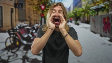 Avuçlanmış eller arasından bağıran bir adam sokakta ağzını açarak iletişim kuruyor..