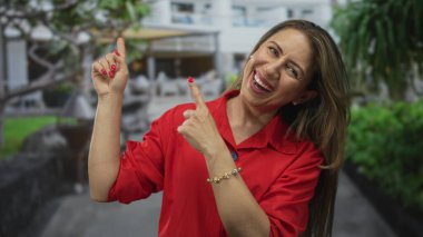 Kadın, yeşillik ve çiçek dolu taş geçitlerle dolu şehir caddesindeki modern yapıyı işaret ediyor. Mutluluk..