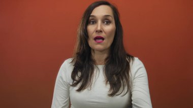 Stüdyo ortamında canlı kırmızı arkaplan karşısında şaşkınlığını dile getiren kadın duygu ve yoğunluğu yakalıyor..