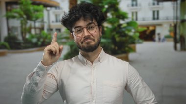 Sakallı, yeşil ve bulanık şehir geçmişi olan bir sokakta gülümseyen genç bir İspanyol..