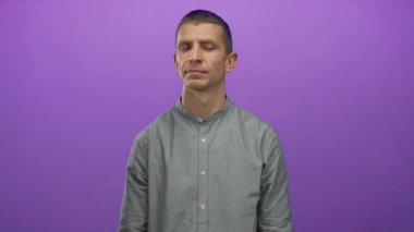 Canlı mor bir arka plan karşısında duran düşünceli bir adam, kapalı alanda izole edilmiş, ince bir hareketle merak ve ilgi gösteren bir adam..