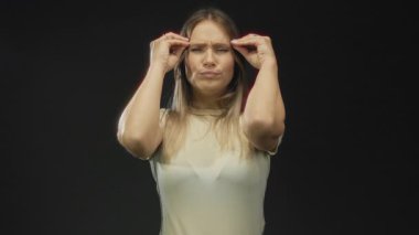 Sarışın beyaz kadın, izole edilmiş siyah arka plana karşı patlayıcı bir jest yapıyor yoğun duygu ve şaşkınlığını dile getirirken sahnenin dramatik havasını vurguluyor..