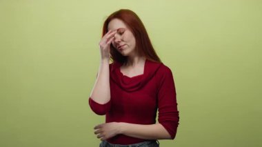 Kırmızı kazak giyen, sarı arka planda duran, düşünceli bir yüz ifadesi sergileyen, izole bir ortamda güzellik ve tefekkür sergileyen bir kadın.