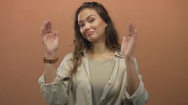 Kadın, stüdyoda kahverengi duvara bakan avuç içi kameralarla el ele tutuşuyor..