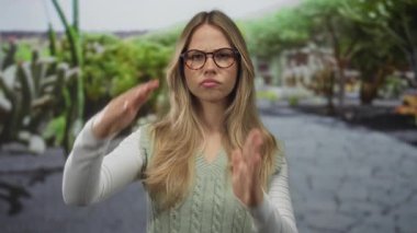 Gözlük takan kadın parkta kollarını göğsüne uzatarak mola hareketi yapıyor; sınır yansımasını duraklat.