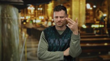 Kilise ortamında jest yapan genç bir adam düşünceli bir ifadeyle modern stili geleneksel altyapıyla harmanlıyor, duyguları ve kültürel karşıtlığı vurguluyor..