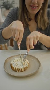 Modern lüks bir restoranda tatlıdan zevk alan bir kadın, bir kapalı kafeteryada leziz bir şekilde dondurulmuş bir pastayla İspanyol güzelliğini ön plana çıkarıyor..
