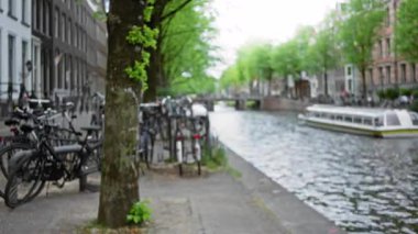 Ağaçlar, bisikletler ve teknelerle bulanık bir kanal manzarası sakin su yolları, canlı yeşillikler ve tarihi mimariyle dolu bir şehir manzarası yaratıyor..