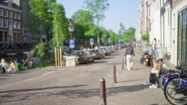 İnsanlar, arabalar ve bisikletlerle Amsterdam Kanalı 'nın bulanık manzarası şehrin Hollanda' daki ikonik kentsel manzarasını vurguluyor..