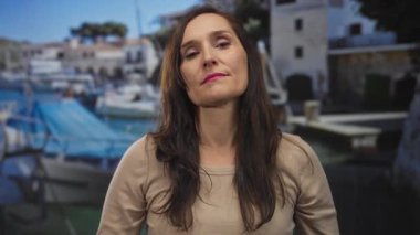 Ciddi ifadeli genç İspanyol kadın, liman kenarında çapraz silah hareketi gösteriyor; reddedilme.