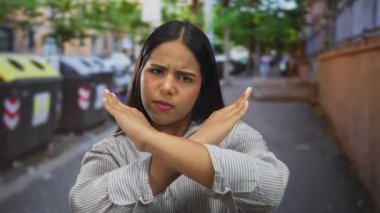 Şehir caddesinde çapraz silahlarla onaylamadığını belirten kadın, şehir manzarasının ortasında dikkat çekmek için bağırarak kararlı duruşunu vurguluyor..
