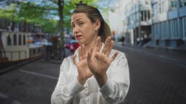 Beyaz düğmeli kadın inşaat yoluyla avuç içiyle el ele tutuşuyor; tiksinti reddediyor..