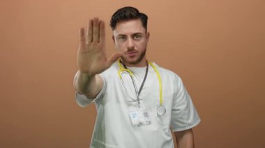 Steteskop takan genç bir doktor, parmakları kahverengi bir fonda değil, profesyonel bir ortamda ciddi bir mesaj taşıyor..