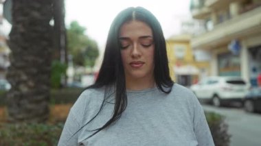 Arka planda canlı mağazaları ve arabaları olan hareketli bir şehir caddesinde güvenle gülümseyen kadın, kentsel güzellik ve çeşitliliği yakalıyor..