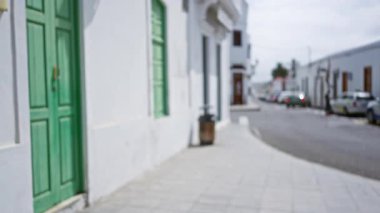 Lanzarote 'de sokak manzarası, yeşil kapılı İspanya, beyaz binalar, bulanık arabalar ve kaldırımlar, kanarya adalarının mimarisi ve atmosferini gözler önüne seriyor.