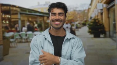 İspanyol adam açık hava restoranının terasında masaları ve sandalyeleri görünür, mutluluk bağlantıları olan bir jest yapıyor..