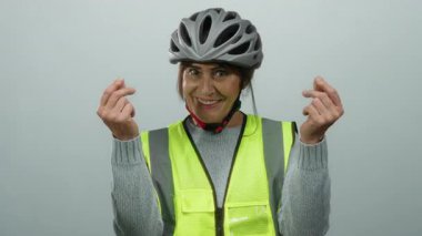 Hispanic senior woman wearing a helmet and reflective vest smiling with isolated white background, making gestures implying spending money.