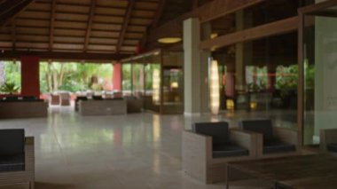 Lüks otel lobisi, modern mobilyalarıyla şık koltuklar ve doğal ışıklandırmanın bulunduğu geniş bir tatil köyü. Hoş bir tropikal atmosfer yaratıyor..