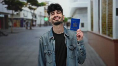 Elinde Küba pasaportu olan gülümseyen bir adam şehir sokaklarında gezmeye hazır ve şehir arka planında bulanık bir kimliğe sahip..