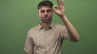 Gözlüklü genç İspanyol gözlüklü adam yeşil stüdyoya bakıyor. Onaylandı..