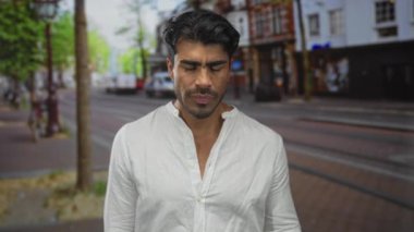 Genç İspanyol adam, şehir caddesindeki bir binanın ön cephesinde sessizlik için parmaklarını dudaklarına işaret eder..