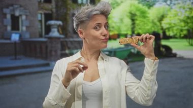 Kadın caddenin dışında çıplak elleriyle gevrek gevrek bir çubuk tutuyor ve gülümsüyor..