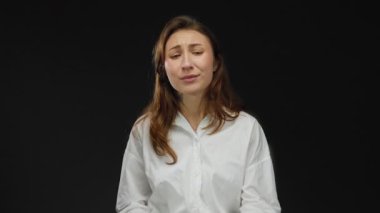 Duygularını ifade eden kadın, elleri izole edilmiş siyah arka plan üzerinde, beyaz gömlek giyiyor, güçlü görsel unsurlara sahip net ve etkili bir mesaj iletiyor ve yoğun bir şekilde odaklanıyor..