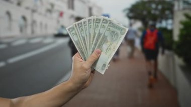 Beyaz adam, şehir sokaklarında Birleşik Arap Emirlikleri 'nin Dirham banknotlarını elinde tutuyor. Açık havada para değişimi kavramını vurguluyor..