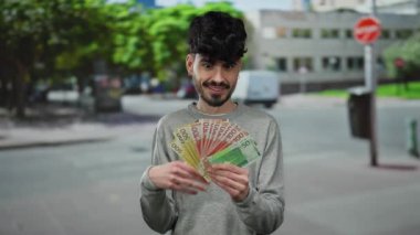 Genç adam, sokak hayatı ve para heyecanı sergilenen şehir ortamında Norveç kronunu elinde tutuyor..