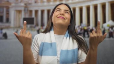 Genç Latin bir kadın San Pedro Meydanı 'nda poz verirken kadınlar parmaklarını kaldırıp Vatikan turistlerini selamlıyor..