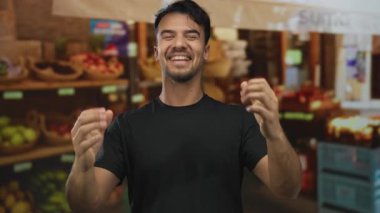 Genç İspanyol bir adam açık hava meyve pazarında duruyor taze ürünler ve canlı renkler arasında coşkuyla gülümsüyor canlı piyasa atmosferi sergiliyor.