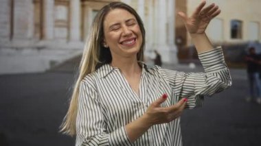 Tarihi şehir caddesinde gülümseyen ve el kol hareketi yapan kadın; mutluluk bağlantısını paylaşan kültür.
