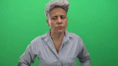 Stüdyoda sessizlik için parmakları dudaklarına kadar uzanan çizgili kısa saçlı beyaz kadın..