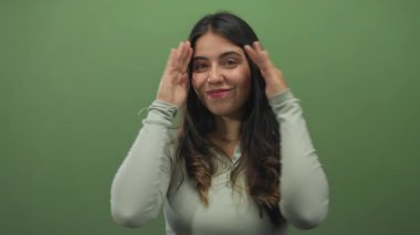 Uzun siyah saçlı genç İspanyol kadın stüdyoda el ele tutuşup gülümsüyor, mutlu bir selamlama..