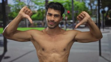 Tişörtsüz, genç, İspanyol, çıplak göğsü kalabalık caddede çifte baş parmak hareketi gösteriyor. Onaylamıyor..