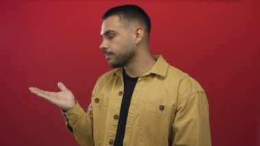 Avuç içi kırmızı stüdyoda elini göğüs hizasında tutan adam kahverengi ceket ve siyah gömlek giyer; belirsizlik.