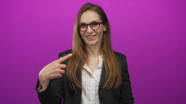 Mor stüdyoda gülümseyen kadın, beyaz gömlek yerine kahverengi saç ve blazer ceket giyer..