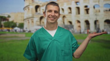 Tıp üniformalı adam, Roma Kolezyumu 'nun önünde gözlerini kapatmış gülümsüyor ve elini uzatıyor. Sanki tarihi bir eser sunuyormuş gibi..
