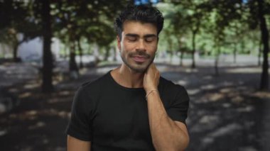 Orman yolunda yeşil ağaçların arasında eli boynunda bir adam, gözleri yavaşça kapalı, hafif baş eğik; rahatlama.